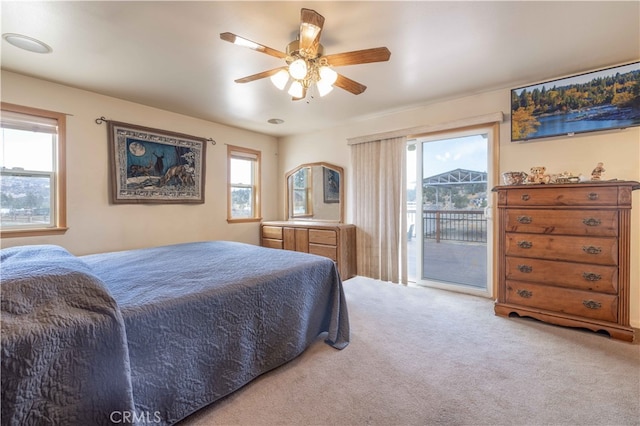 carpeted bedroom featuring access to outside, multiple windows, and ceiling fan