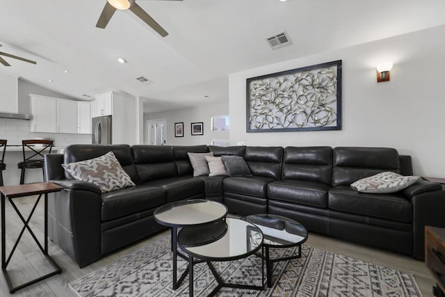 living room with ceiling fan, hardwood / wood-style floors, and vaulted ceiling