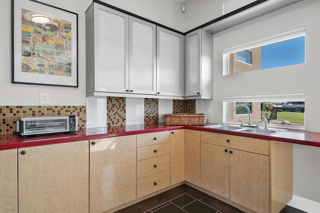 kitchen with tasteful backsplash, dark tile patterned floors, and sink