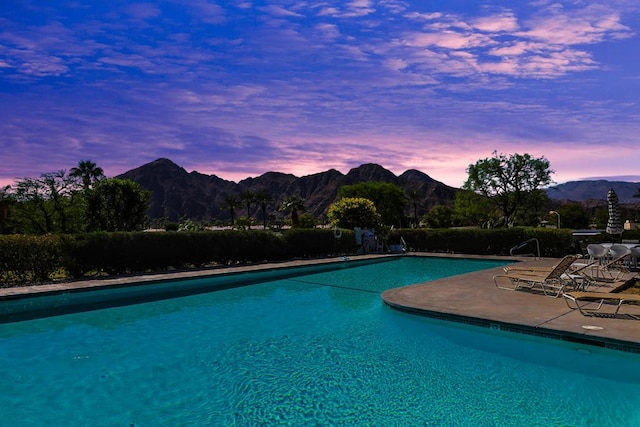 pool at dusk with a mountain view and a patio area