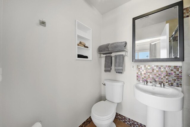 bathroom with decorative backsplash and toilet