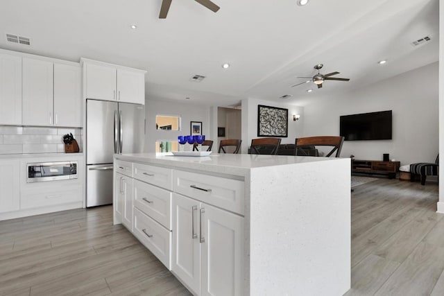 kitchen featuring white cabinetry, light hardwood / wood-style flooring, a kitchen island, and appliances with stainless steel finishes