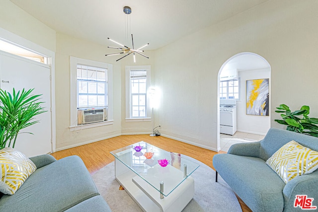 living room with cooling unit, light hardwood / wood-style floors, and a notable chandelier