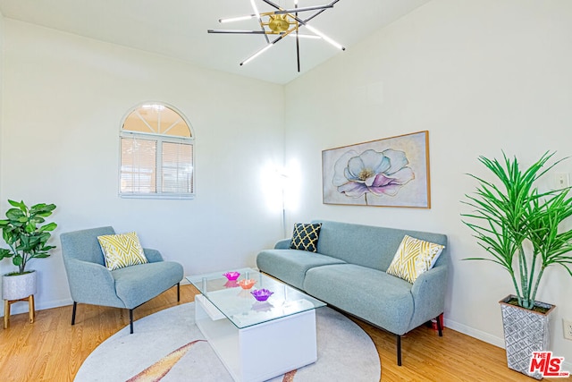 living room featuring an inviting chandelier, vaulted ceiling, and light wood-type flooring