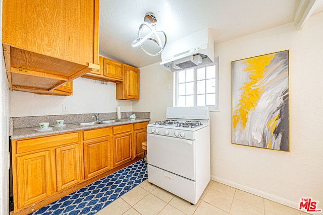 kitchen featuring white gas stove, light tile patterned floors, and sink