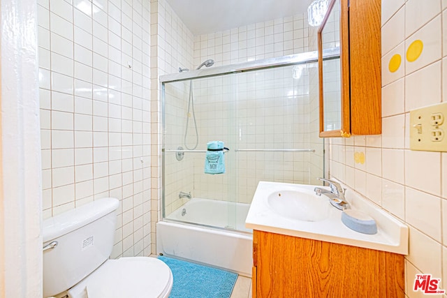 full bathroom featuring vanity, toilet, tile walls, and enclosed tub / shower combo