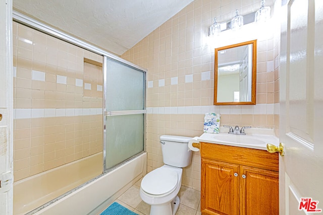 full bathroom with tile patterned flooring, vaulted ceiling, toilet, and tile walls