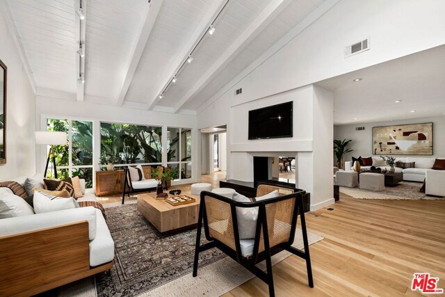 living room with beamed ceiling, rail lighting, high vaulted ceiling, and light hardwood / wood-style flooring