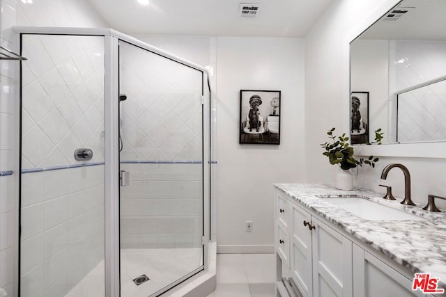 bathroom featuring tile patterned flooring, vanity, and walk in shower