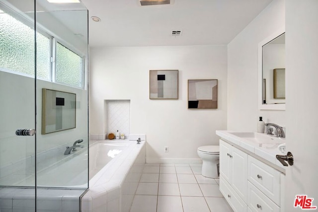 bathroom featuring tile patterned floors, a relaxing tiled tub, toilet, and vanity