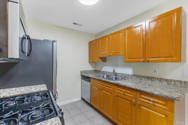 kitchen with light stone counters, light tile patterned floors, sink, and appliances with stainless steel finishes