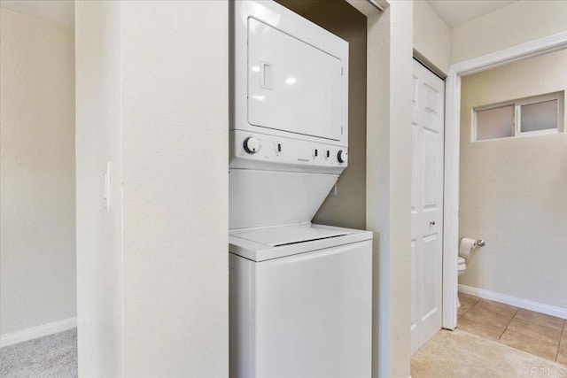 laundry room featuring light tile patterned floors and stacked washer and clothes dryer