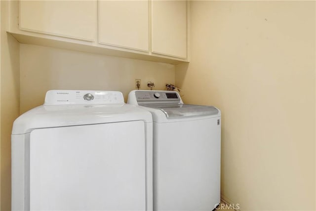 clothes washing area featuring cabinets and washing machine and dryer