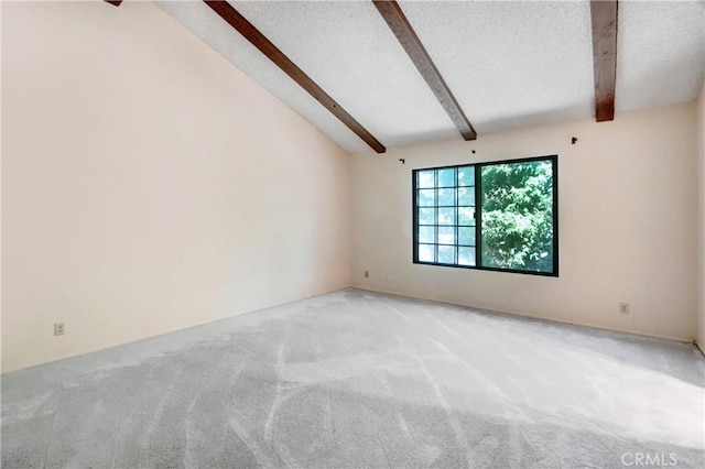 carpeted empty room with lofted ceiling with beams and a textured ceiling