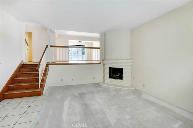 unfurnished living room featuring ceiling fan, light carpet, and a brick fireplace