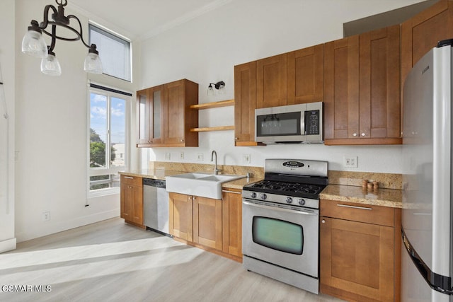 kitchen featuring light wood-type flooring, sink, pendant lighting, crown molding, and stainless steel appliances