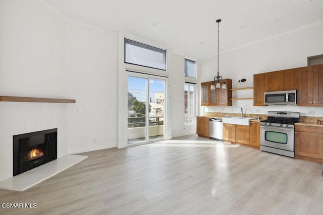 kitchen featuring sink, decorative light fixtures, stainless steel appliances, and light wood-type flooring