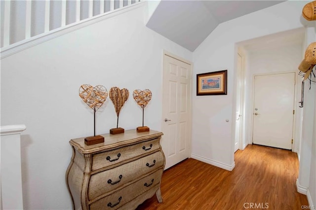 corridor with lofted ceiling and light hardwood / wood-style flooring