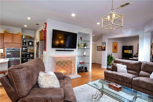 living room with an inviting chandelier and light hardwood / wood-style flooring