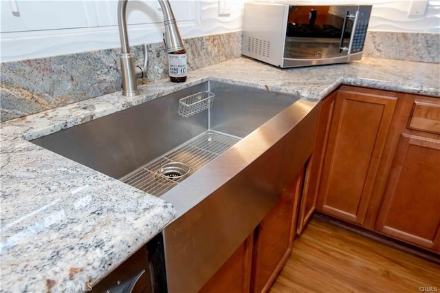 kitchen featuring light stone countertops, light hardwood / wood-style flooring, and sink