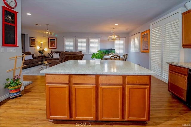 kitchen featuring light stone countertops, light hardwood / wood-style flooring, hanging light fixtures, and a center island