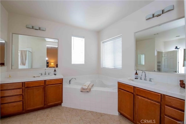 bathroom with vanity, tiled bath, and tile patterned flooring