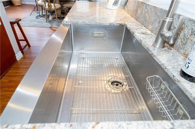 details featuring dark wood-type flooring, light stone countertops, and sink