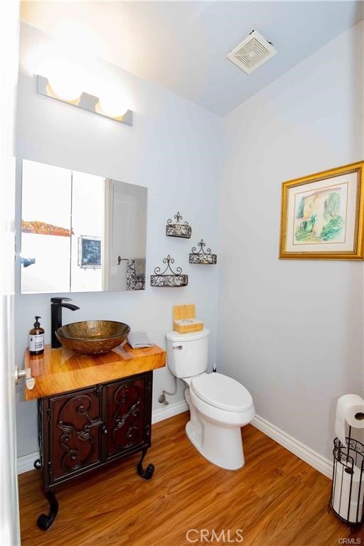 bathroom featuring hardwood / wood-style flooring, toilet, and vanity