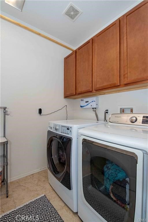 laundry room featuring separate washer and dryer, light tile patterned floors, and cabinets