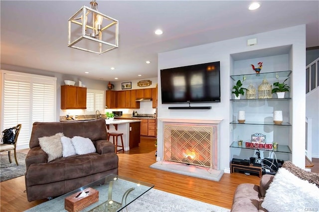 living room featuring light hardwood / wood-style floors, an inviting chandelier, and sink