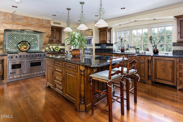 kitchen featuring hanging light fixtures, sink, a kitchen island, backsplash, and stainless steel appliances