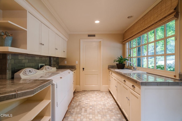 washroom with ornamental molding, washer and clothes dryer, sink, and cabinets