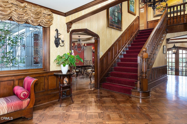 entryway with french doors, a notable chandelier, dark parquet flooring, and ornamental molding