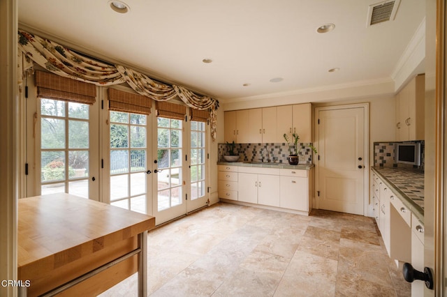 kitchen with crown molding, french doors, and tasteful backsplash