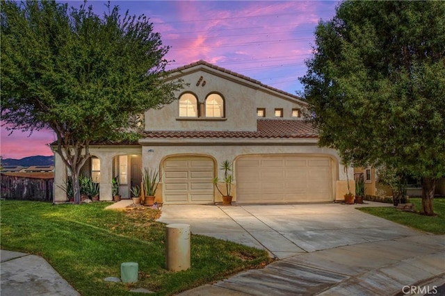 mediterranean / spanish home with a tiled roof, concrete driveway, stucco siding, a lawn, and a garage