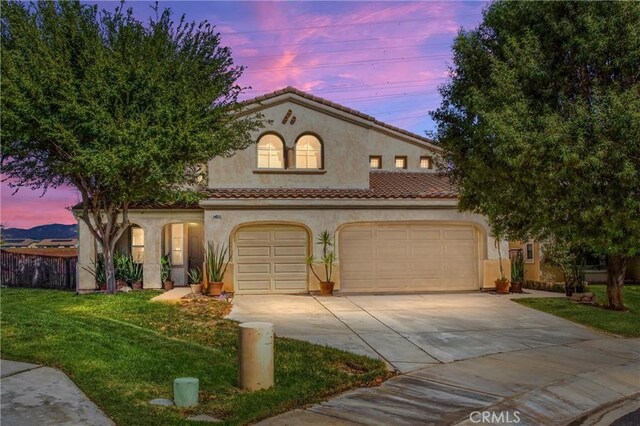 mediterranean / spanish home with a tiled roof, concrete driveway, stucco siding, a lawn, and a garage