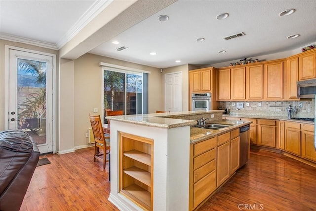 kitchen featuring decorative backsplash, stainless steel appliances, a kitchen island with sink, crown molding, and wood-type flooring