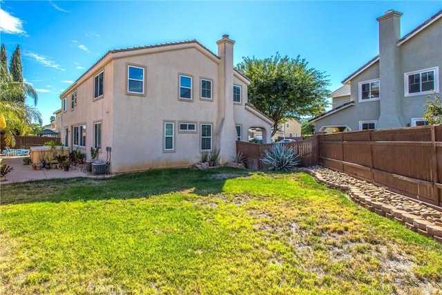 rear view of house with a lawn, stucco siding, a chimney, a fenced backyard, and a patio area