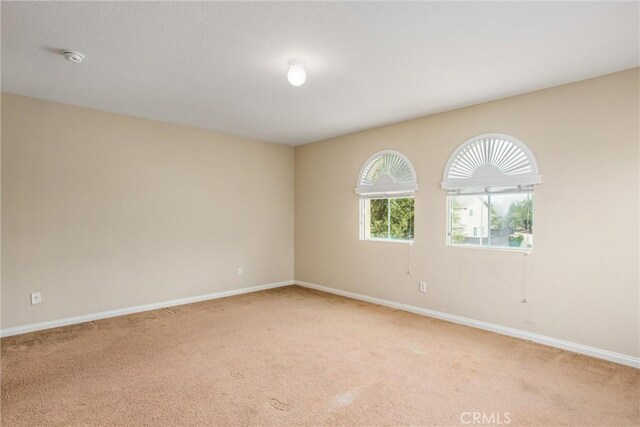 spare room featuring baseboards and light carpet