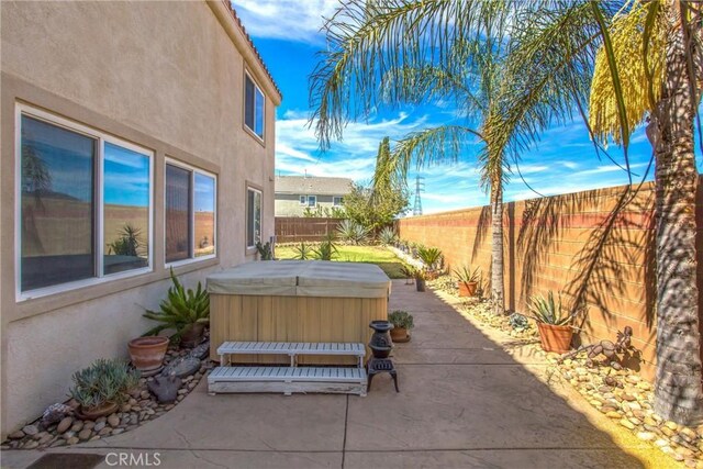 view of patio featuring a hot tub and a fenced backyard