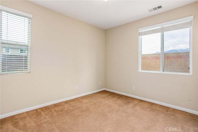 spare room with visible vents, light colored carpet, and baseboards