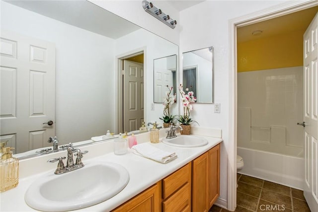 bathroom featuring tile patterned floors, toilet, double vanity, and a sink