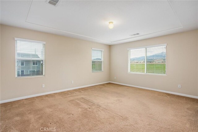 empty room featuring visible vents, carpet floors, and baseboards