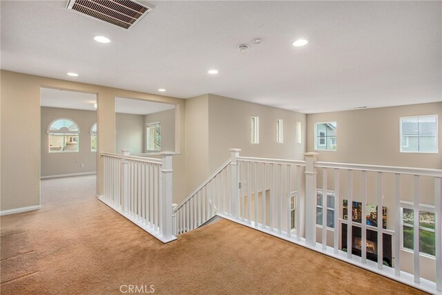 hall featuring visible vents, an upstairs landing, recessed lighting, carpet, and baseboards