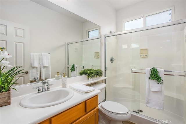 bathroom with a stall shower, toilet, and vanity