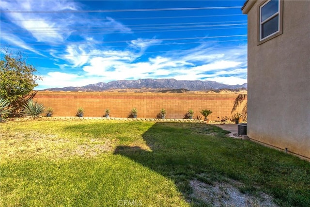 view of yard with central air condition unit, a mountain view, and fence