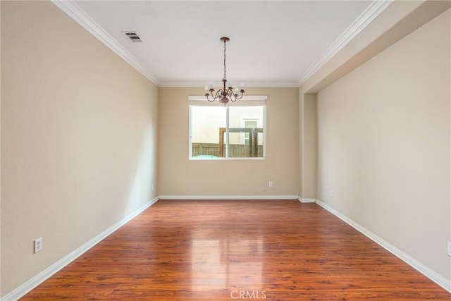 unfurnished room featuring visible vents, a notable chandelier, wood finished floors, and ornamental molding