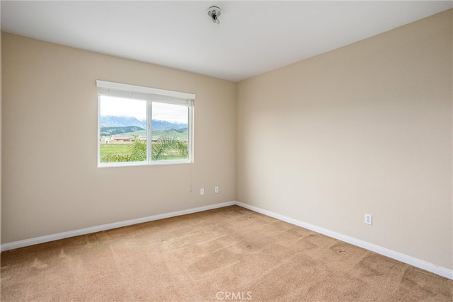 spare room with baseboards and light carpet