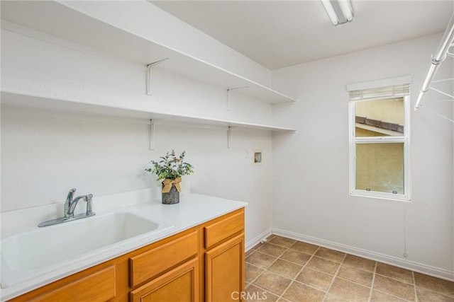 laundry area with baseboards, washer hookup, laundry area, light tile patterned flooring, and a sink