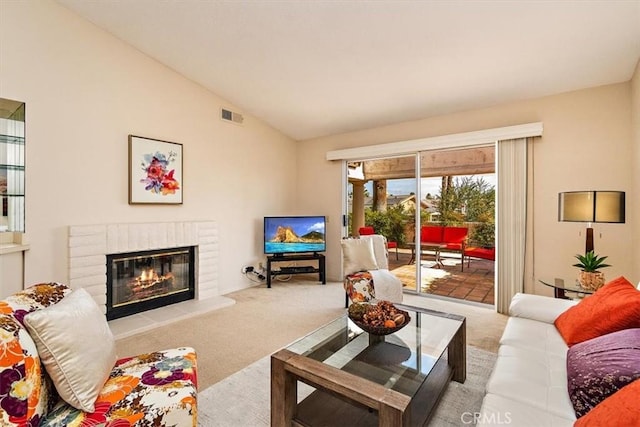 carpeted living room with a brick fireplace and vaulted ceiling